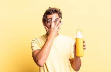 Şok olmuş, korkmuş ya da dehşete düşmüş gibi görünen, yüzünü çay termosuyla kaplayan çılgın adam.