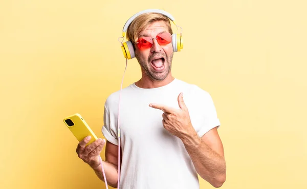 Blond Adult Man Looking Excited Surprised Pointing Side Headphones — Stock Photo, Image