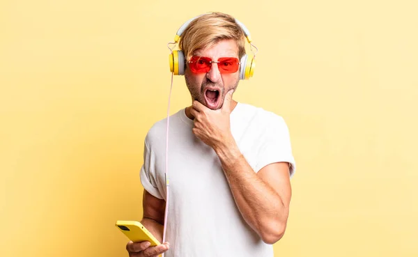 Blond Adult Man Mouth Eyes Wide Open Hand Chin Headphones — Stock Photo, Image
