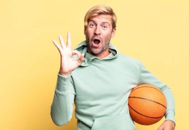 Basketbol topu olan sarışın, yakışıklı yetişkin bir adam.