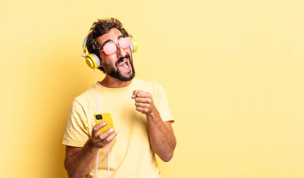 Uttrycksfull Galen Skäggig Man Lyssnar Musik Med Hörlurar Och Sartphone — Stockfoto