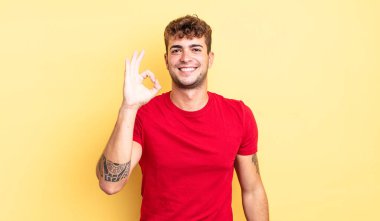 Genç yakışıklı adam mutlu, rahat ve tatmin olmuş hissediyor. Onayını iyi bir hareketle gösteriyor. Gülümsüyor.