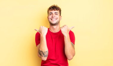 Genç ve yakışıklı adam neşeyle gülümsüyor ve mutlu görünüyor, kaygısız ve pozitif hissediyor.