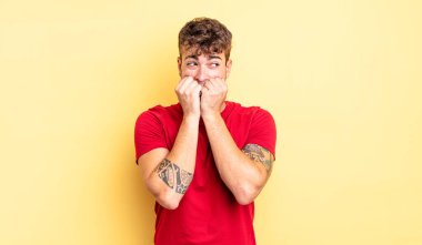 Genç yakışıklı adam endişeli, endişeli, stresli ve korkmuş görünüyor, tırnaklarını yiyor ve yanal fotokopi alanı arıyor.