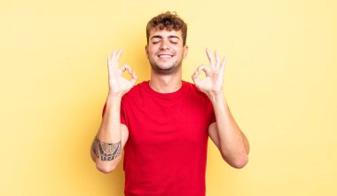 Genç yakışıklı adam konsantre olmuş ve meditasyon yapıyor, kendini tatmin olmuş ve rahatlamış hissediyor, düşünüyor ya da bir seçim yapıyor.