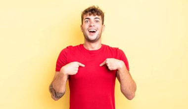 Genç yakışıklı adam mutlu, şaşkın ve gururlu, heyecanlı, şaşkın bakışlarıyla kendini işaret ediyor.