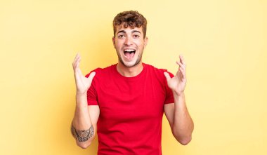 Genç yakışıklı adam mutlu, heyecanlı, şaşırmış ya da şok olmuş hissediyor, gülümsüyor ve hayrete düşüyor.