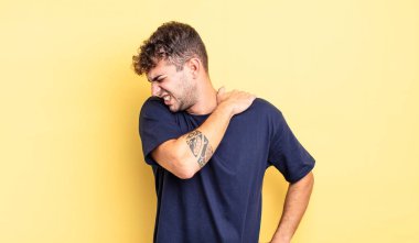 Genç yakışıklı adam yorgun, stresli, endişeli, hayal kırıklığına uğramış ve depresyonda, sırtı ya da boynu ağrıyan