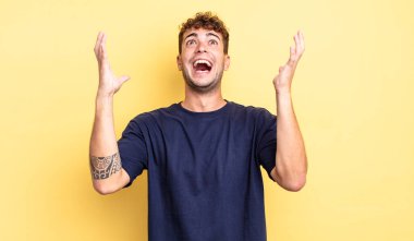 Genç yakışıklı adam kendini mutlu, şaşkın, şanslı ve şaşırmış hissediyor. Zaferi kutlarken iki elini de havaya kaldırıyor.