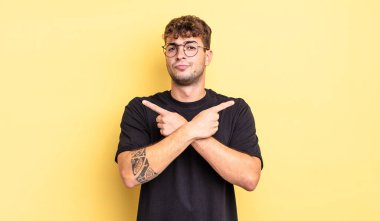 Şaşkın, kafası karışmış, güvensiz ve şüpheyle zıt yönlere bakan genç yakışıklı bir adam.