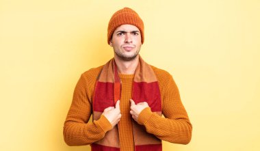 Genç ve yakışıklı bir adam kendini işaret ediyor. Şaşırmış ve şaşırmış bir şekilde bakıyor.