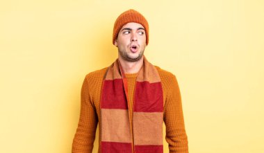 Genç yakışıklı adam şok olmuş, mutlu, şaşkın ve şaşırmış hissediyor, ağzı açık bir şekilde yana bakıyor.