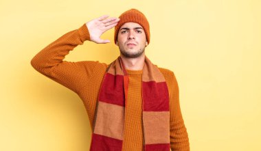 Genç ve yakışıklı bir adam saygı göstererek, onur ve vatanseverlik adına askeri bir selamla kamerayı selamlıyor.