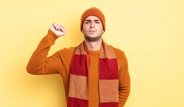 Genç yakışıklı adam ciddi, güçlü ve asi hissediyor, yumruğunu kaldırıyor, protesto ediyor ya da devrim için savaşıyor.