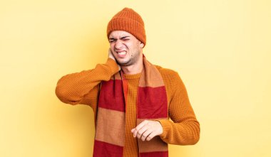 Genç ve yakışıklı bir adam stresli, hayal kırıklığına uğramış ve yorgun, endişeli ve sorunlu bir bakışla boynunu okşuyor.