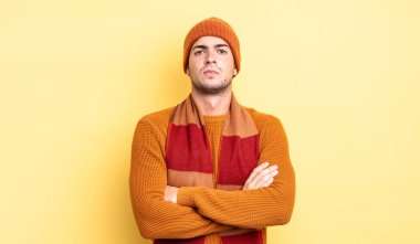 Genç yakışıklı adam hayal kırıklığına uğramış ve hayal kırıklığına uğramış, ciddi görünüyor, kızgın ve kollarını kavuşturmuş.