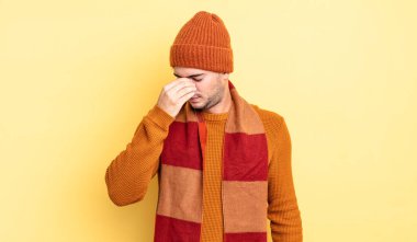 Genç yakışıklı, stresli, mutsuz ve hayal kırıklığına uğramış, alınlı ve şiddetli baş ağrısı çeken bir adam.