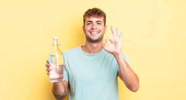 Genç yakışıklı adam kendini mutlu hissediyor, iyi bir jestle onaylıyor. su kavramı