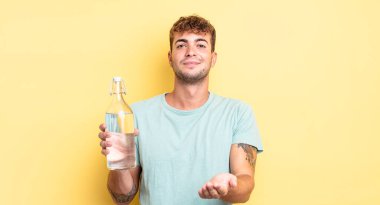 Genç ve yakışıklı bir adam arkadaşça gülümsüyor ve bir konsept sunuyor. su kavramı