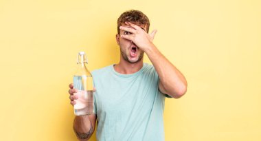 Genç, yakışıklı adam şok olmuş, korkmuş ya da korkmuş görünüyor. su kavramı