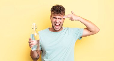 Genç yakışıklı adam mutsuz ve stresli görünüyor, intihar jesti silah işareti yapıyor. su kavramı