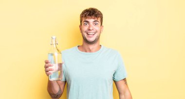 Genç yakışıklı adam mutlu ve hoş bir şekilde şaşırmış görünüyor. su kavramı