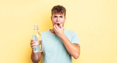 Ağzı ve gözleri açık ve eli çenesinde genç yakışıklı bir adam. su kavramı