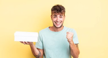 Genç yakışıklı adam şok olmuş hissediyor, gülüyor ve başarıyı kutluyor. beyaz kutu kavramı