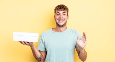 Genç yakışıklı adam kendini mutlu hissediyor ve inanılmaz bir şeye hayret ediyor. beyaz kutu kavramı