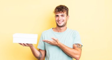 Genç yakışıklı adam neşeyle gülümsüyor, mutlu hissediyor ve bir konsept gösteriyor. beyaz kutu kavramı