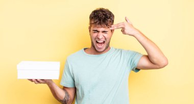 Genç yakışıklı adam mutsuz ve stresli görünüyor, intihar jesti silah işareti yapıyor. beyaz kutu kavramı