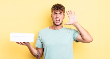 Genç yakışıklı adam ellerini havaya kaldırarak çığlık atıyor. beyaz kutu kavramı