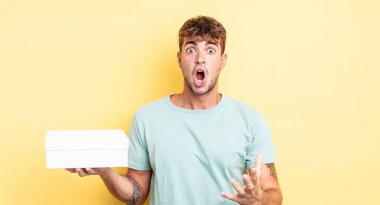 Genç ve yakışıklı bir adam şok olmuş ve şaşırmış hissediyor. beyaz kutu kavramı