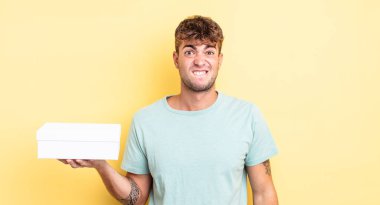 Kafası karışmış ve kafası karışmış genç yakışıklı bir adam. beyaz kutu kavramı