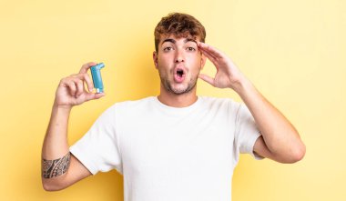 Genç yakışıklı adam mutlu, şaşkın ve şaşırmış görünüyor. astım konsepti