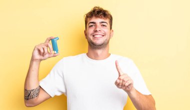 Genç yakışıklı adam gururla gülümsüyor ve kendinden emin bir numara oluyor. astım konsepti