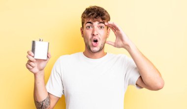 Genç yakışıklı adam mutlu, şaşkın ve şaşırmış görünüyor. alkol şişesi konsepti