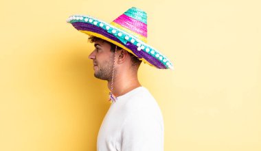 Profilde genç yakışıklı bir adam hayal kuruyor, hayal kuruyor ya da hayal kuruyor. Meksika şapkası konsepti