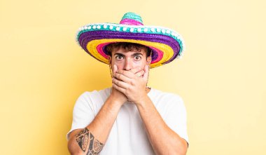 Genç ve yakışıklı bir adam elleri ile ağzını kapatıyor ve şok geçiriyor. Meksika şapkası konsepti