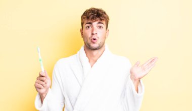 Genç, yakışıklı adam şaşırmış ve şok olmuş görünüyor. Çenesi düşmüş, elinde bir nesne var. diş fırçası kavramı