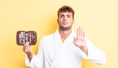 Genç ve yakışıklı adam ciddi görünüyor. Avuç içi gösteriyor. Durdurma hareketi yapıyor. çivi araçları çanta konsepti