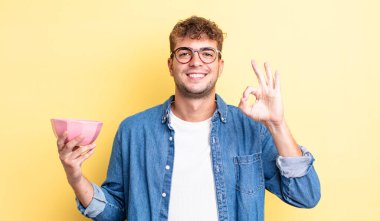 Genç yakışıklı adam kendini mutlu hissediyor, iyi bir jestle onaylıyor. boş kase kavramı