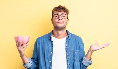 Genç yakışıklı adam şaşkın, şaşkın ve şüpheci hissediyor. boş kase kavramı