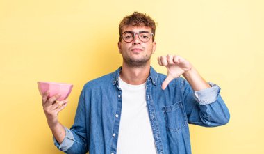 Genç ve yakışıklı bir adam kendini kötü hissediyor, baş parmağını kaldırıyor. boş kase kavramı