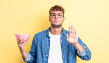 Genç ve yakışıklı adam ciddi görünüyor. Avuç içi gösteriyor. Durdurma hareketi yapıyor. boş kase kavramı