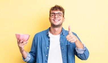 Genç ve yakışıklı bir adam gururlu, olumlu gülümsüyor. boş kase kavramı