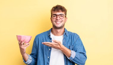 Genç yakışıklı adam neşeyle gülümsüyor, mutlu hissediyor ve bir konsept gösteriyor. boş kase kavramı