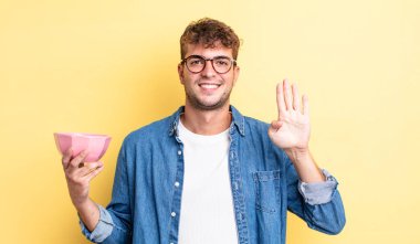 Genç yakışıklı adam gülümsüyor ve arkadaş canlısı görünüyor, dört numarayı gösteriyor. boş kase kavramı