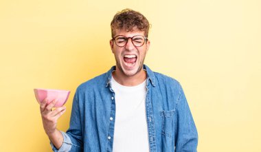 Genç yakışıklı adam agresif bir şekilde bağırıyor, çok kızgın görünüyor. boş kase kavramı