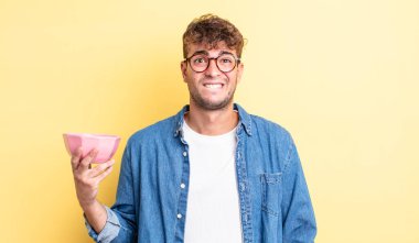 Kafası karışmış ve kafası karışmış genç yakışıklı bir adam. boş kase kavramı